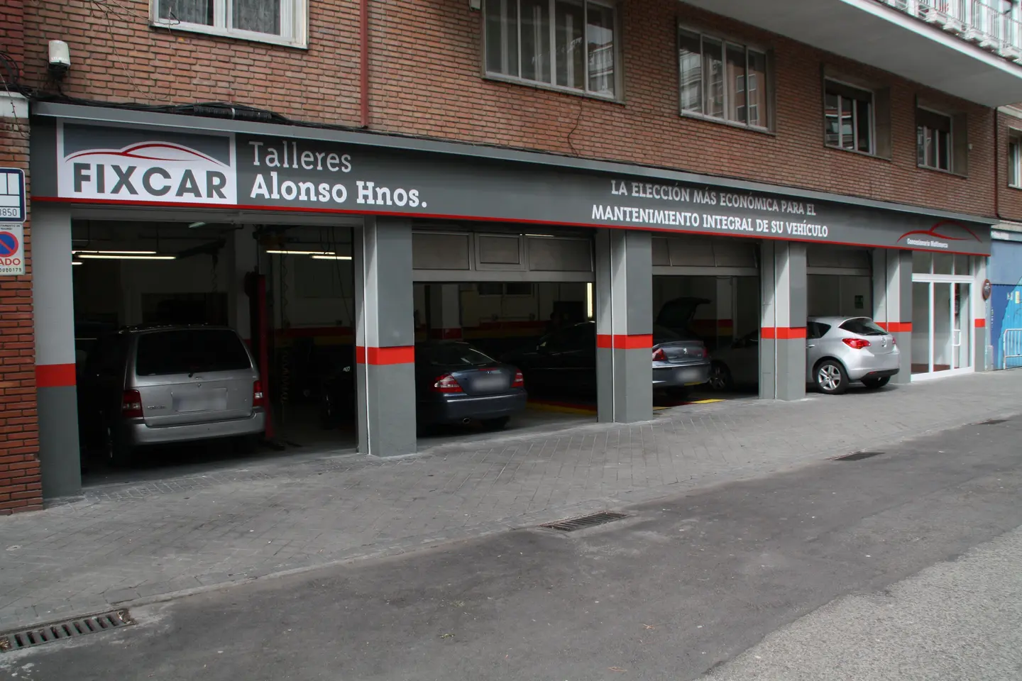Fachada de Talleres Alonso Hermanos en la calle Bristol, con los boxes del taller abiertos