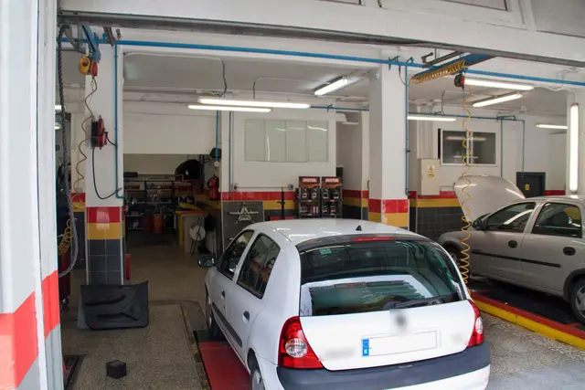 Interior del taller con los boxes de trabajo y un coche en el elevador