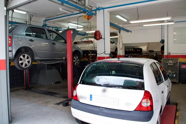 Coche elevado en uno de los boxes, con mangueras y equipos del taller